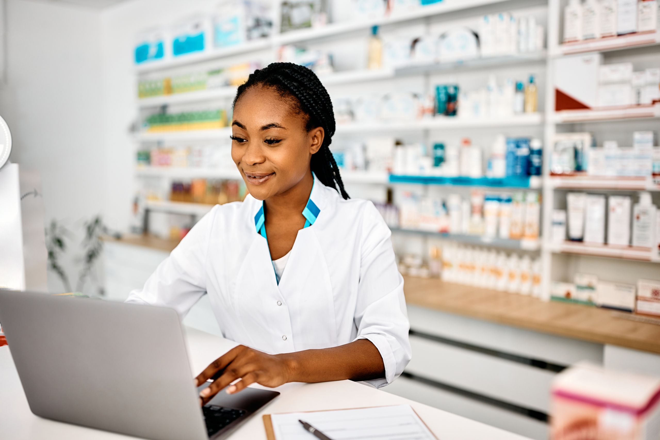 Young black pharmacist using laptop while working in a pharmacy.